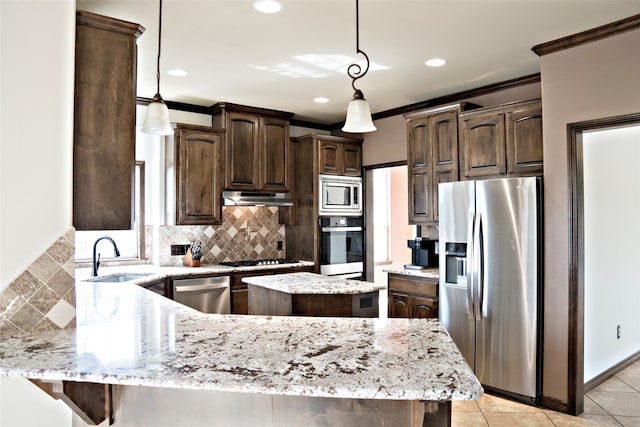 kitchen with dark brown cabinets, appliances with stainless steel finishes, a kitchen island, and sink