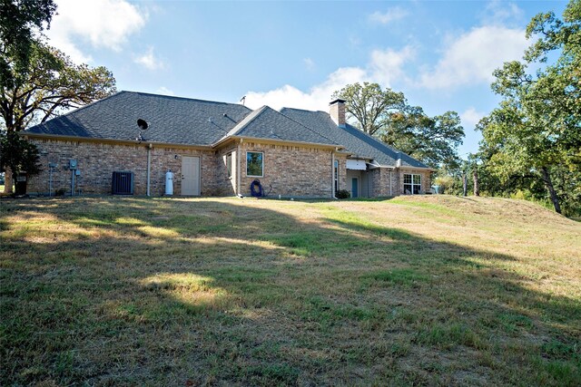 7226 County Road 1504, Athens, TX 75751 - rear view of property featuring a chimney, a lawn, brick siding, cooling unit, and roof with shingles