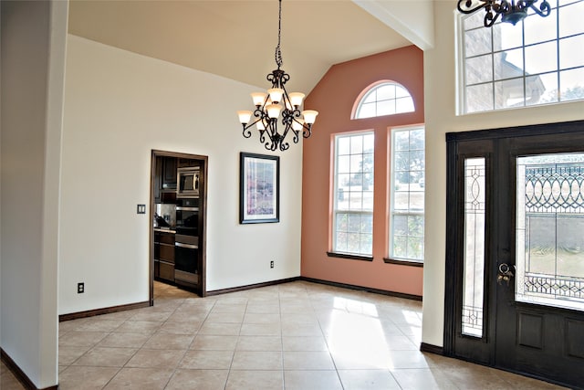 tiled entryway featuring an inviting chandelier and vaulted ceiling