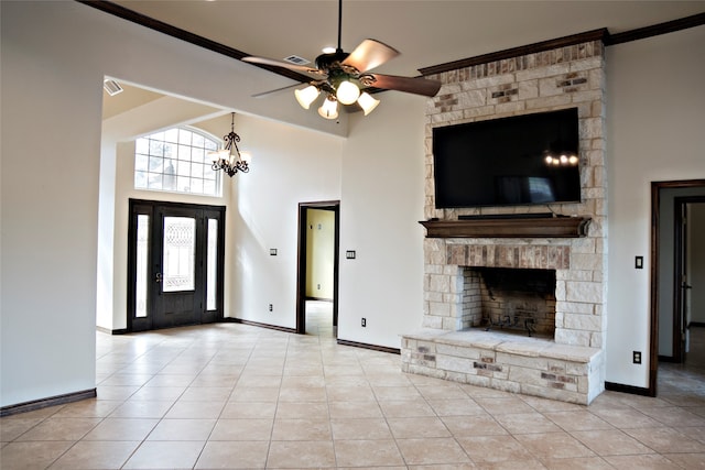 unfurnished living room featuring ceiling fan with notable chandelier, a fireplace, a towering ceiling, and crown molding