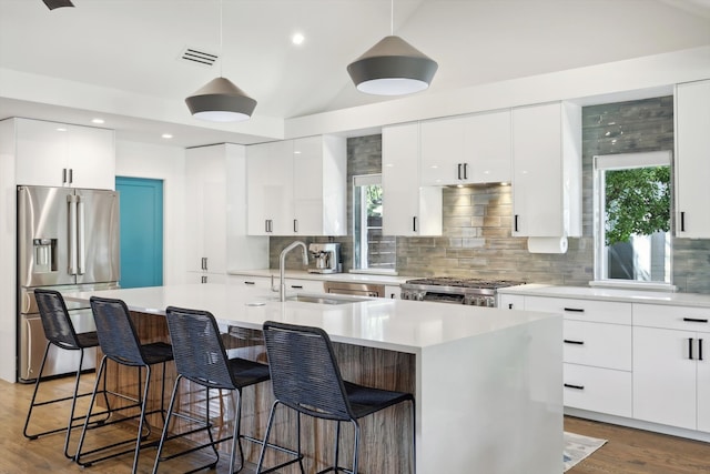 kitchen featuring pendant lighting, a center island with sink, appliances with stainless steel finishes, and dark hardwood / wood-style flooring