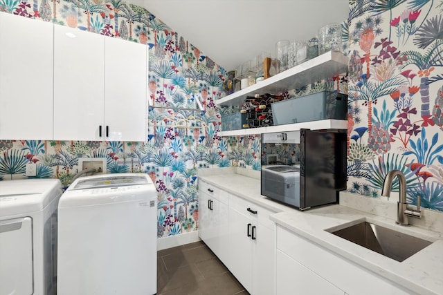 laundry area with cabinets, dark tile patterned flooring, washing machine and dryer, and sink