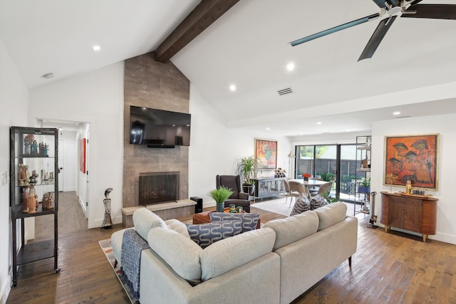 living room with high vaulted ceiling, a tiled fireplace, beam ceiling, ceiling fan, and hardwood / wood-style flooring