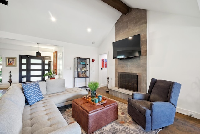 living room with lofted ceiling with beams, dark wood-type flooring, and a large fireplace