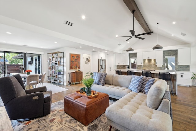 living room featuring ceiling fan, vaulted ceiling with beams, and light wood-type flooring