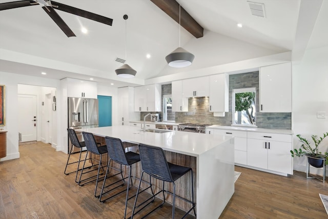 kitchen featuring vaulted ceiling with beams, white cabinetry, wood-type flooring, and stainless steel appliances