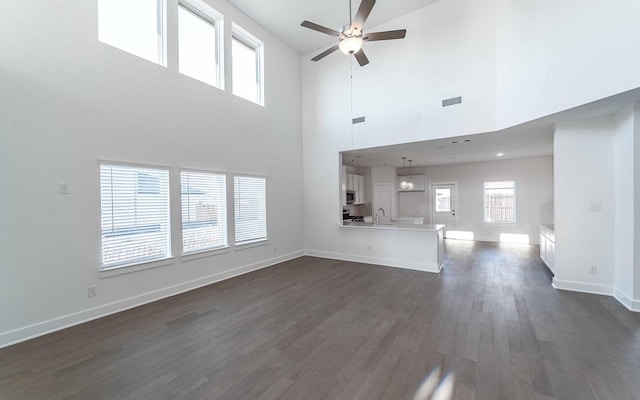 unfurnished living room featuring ceiling fan, dark hardwood / wood-style flooring, a towering ceiling, and sink