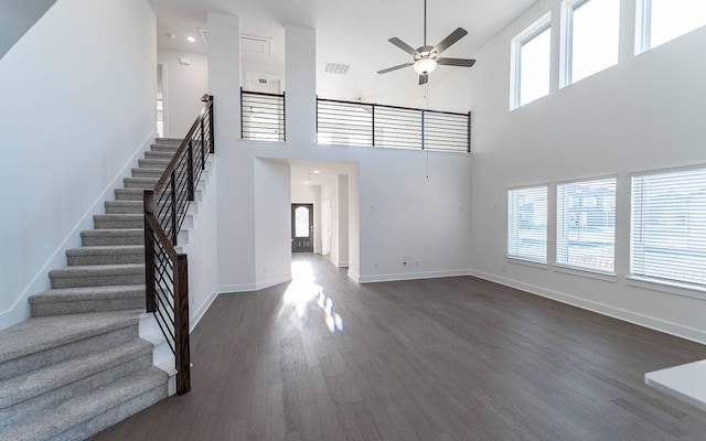 unfurnished living room featuring ceiling fan, dark hardwood / wood-style flooring, and a high ceiling