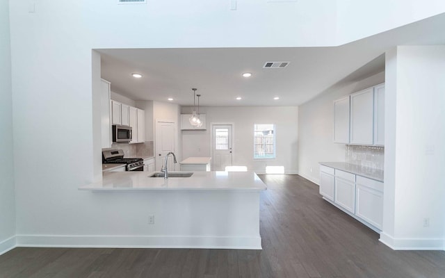 kitchen featuring decorative backsplash, appliances with stainless steel finishes, sink, pendant lighting, and white cabinets