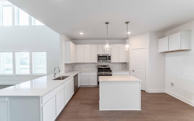 kitchen featuring a center island, sink, hanging light fixtures, white cabinetry, and stainless steel appliances