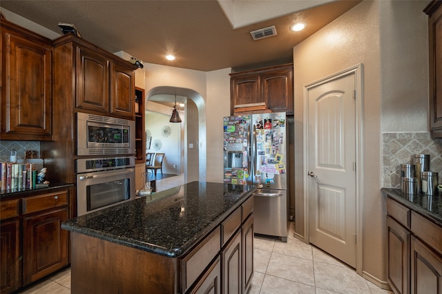 kitchen with stainless steel appliances, backsplash, a center island, and light tile patterned floors