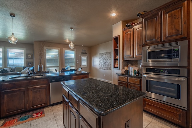 kitchen featuring light tile patterned floors, sink, a kitchen island, a textured ceiling, and appliances with stainless steel finishes