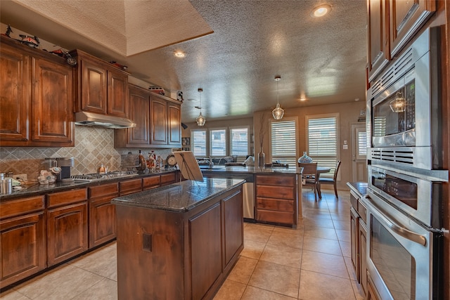 kitchen featuring a textured ceiling, hanging light fixtures, a center island, and light tile patterned floors