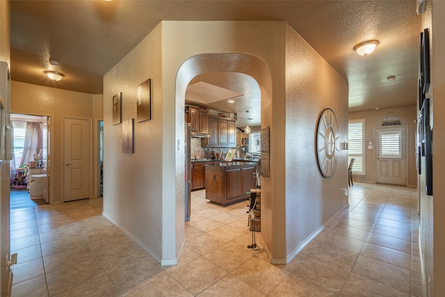 corridor with a textured ceiling and light tile patterned flooring