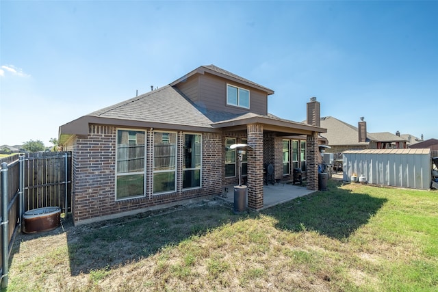 rear view of property featuring a shed, a yard, and a patio area