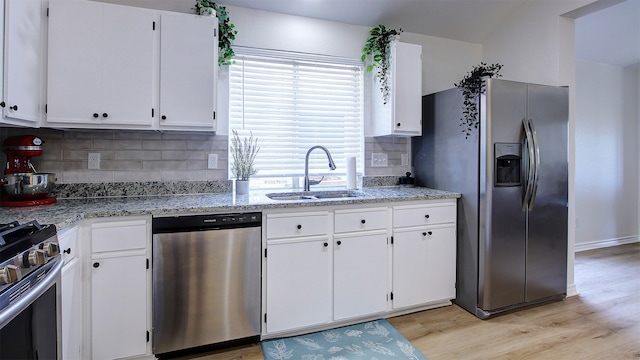 kitchen with white cabinets, light stone countertops, sink, appliances with stainless steel finishes, and light wood-type flooring