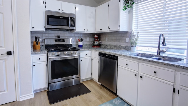 kitchen featuring light hardwood / wood-style floors, tasteful backsplash, sink, white cabinetry, and stainless steel appliances