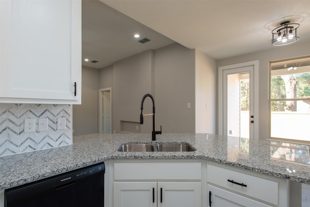 kitchen featuring tasteful backsplash, light stone counters, sink, white cabinets, and black dishwasher