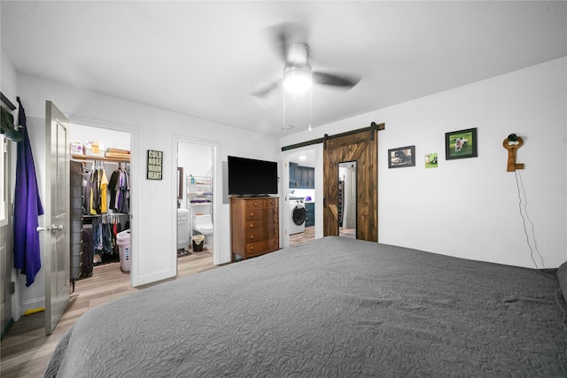 bedroom featuring a closet, a barn door, ensuite bathroom, a spacious closet, and ceiling fan