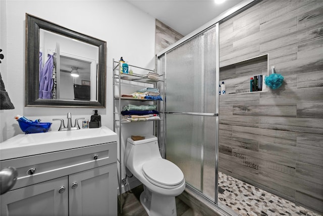 bathroom with wood-type flooring, walk in shower, vanity, and toilet