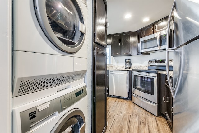 kitchen featuring dark brown cabinets, light hardwood / wood-style floors, appliances with stainless steel finishes, and stacked washing maching and dryer