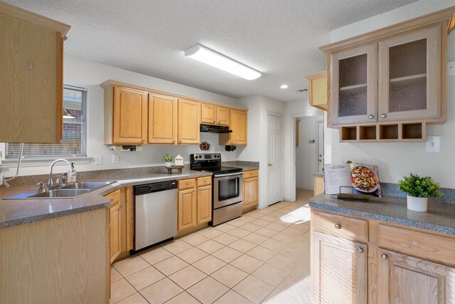 kitchen featuring appliances with stainless steel finishes, light brown cabinetry, hanging light fixtures, and light tile patterned floors