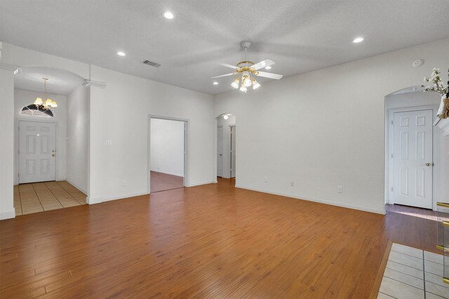 unfurnished living room featuring ceiling fan, hardwood / wood-style floors, a tile fireplace, and a textured ceiling