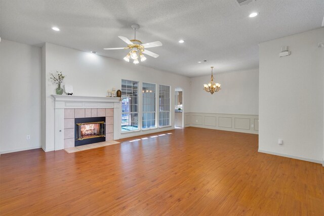 unfurnished living room with ceiling fan with notable chandelier, a textured ceiling, and light hardwood / wood-style floors