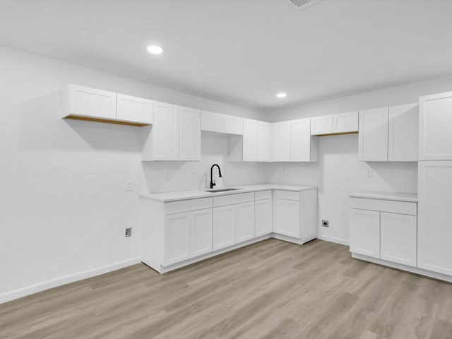 kitchen with white cabinets, light wood-type flooring, and sink