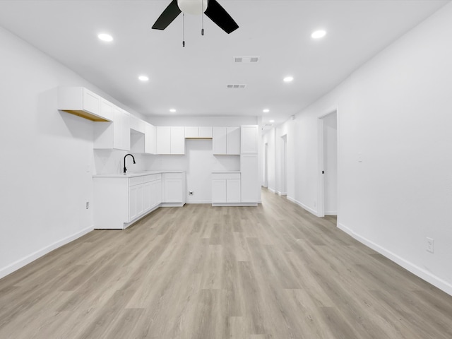 unfurnished living room featuring light wood-type flooring, ceiling fan, and sink