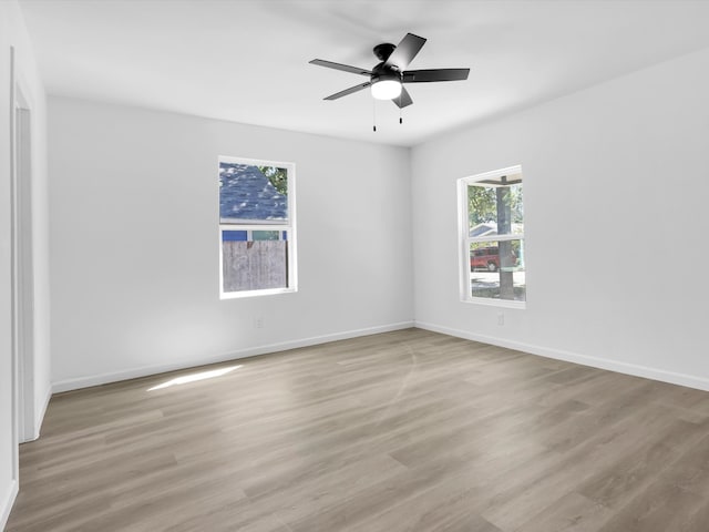 spare room with light hardwood / wood-style flooring, a wealth of natural light, and ceiling fan