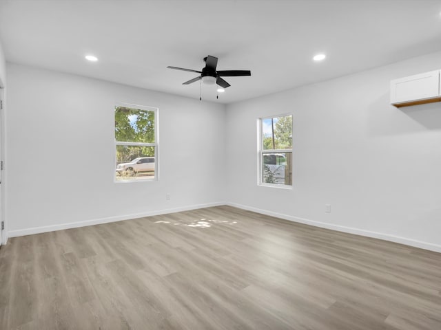 empty room with a wealth of natural light, light hardwood / wood-style floors, and ceiling fan