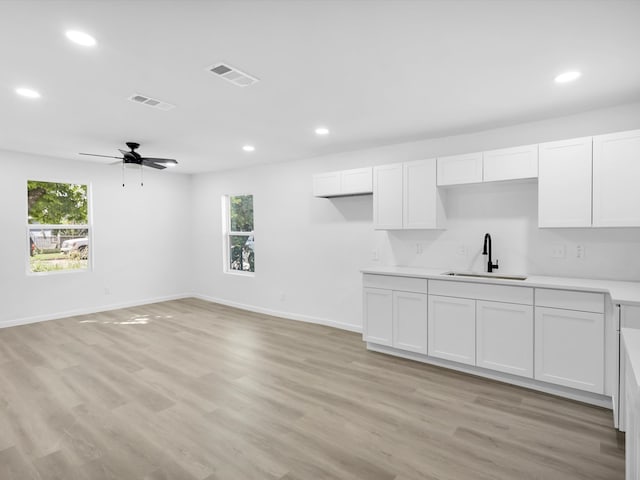 kitchen featuring white cabinets, ceiling fan, light wood-type flooring, and sink