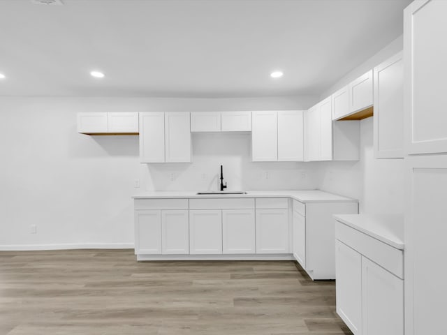 kitchen featuring light wood-type flooring, sink, and white cabinetry