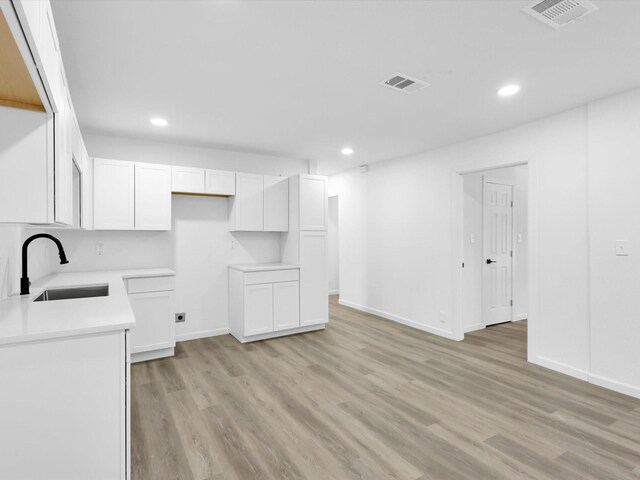 kitchen with white cabinets, light hardwood / wood-style floors, and sink