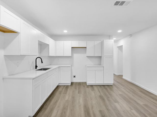 kitchen featuring light wood-type flooring, white cabinetry, and sink