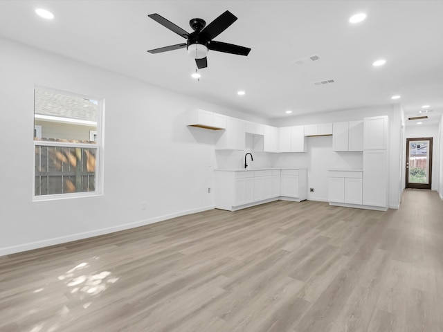 unfurnished living room with ceiling fan, light hardwood / wood-style flooring, and sink