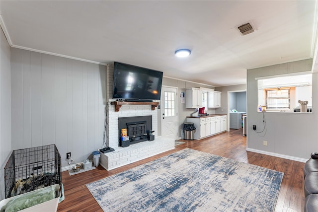 living room featuring wooden walls, dark wood-type flooring, a wood stove, and a healthy amount of sunlight