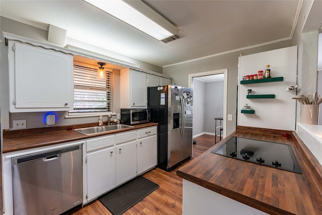 kitchen featuring white cabinets, butcher block counters, stainless steel appliances, light wood-type flooring, and sink