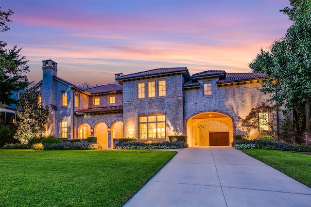 mediterranean / spanish house with a garage and a lawn