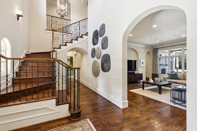 staircase with ornamental molding, hardwood / wood-style floors, and a chandelier