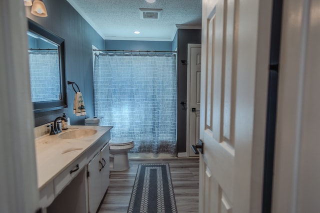 bathroom featuring wood-type flooring, vanity, crown molding, and toilet