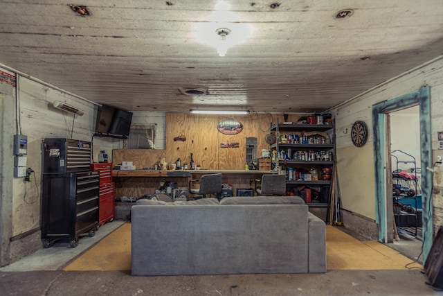 living room featuring wooden walls, concrete flooring, and a workshop area