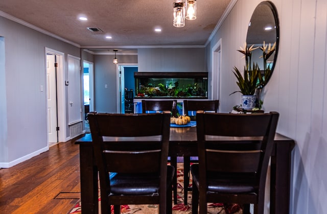 dining space with wood-type flooring, wood walls, a textured ceiling, and crown molding