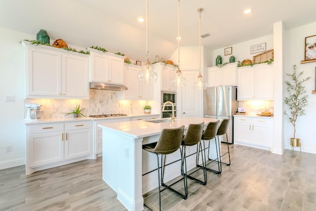 kitchen with sink, stainless steel appliances, white cabinets, and an island with sink