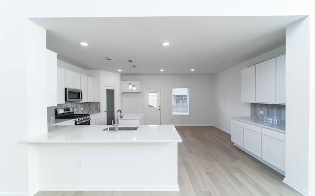 kitchen with pendant lighting, white cabinets, sink, appliances with stainless steel finishes, and tasteful backsplash