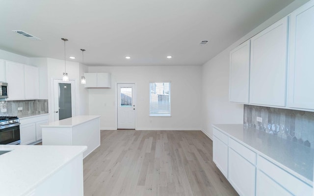 kitchen with stainless steel appliances, light hardwood / wood-style flooring, backsplash, pendant lighting, and white cabinets