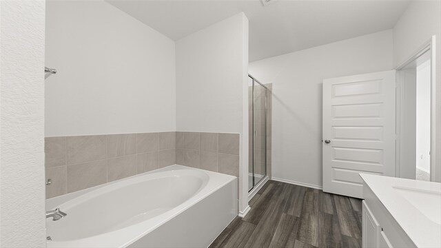 bathroom with hardwood / wood-style flooring, vanity, and shower with separate bathtub