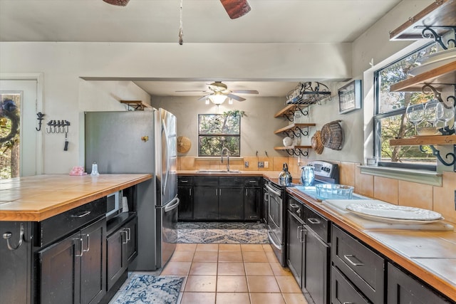 kitchen featuring stainless steel appliances, sink, light tile patterned floors, wood counters, and decorative backsplash