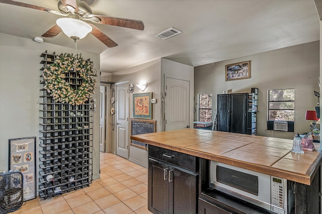 kitchen with tile counters, cooling unit, light tile patterned flooring, and ceiling fan